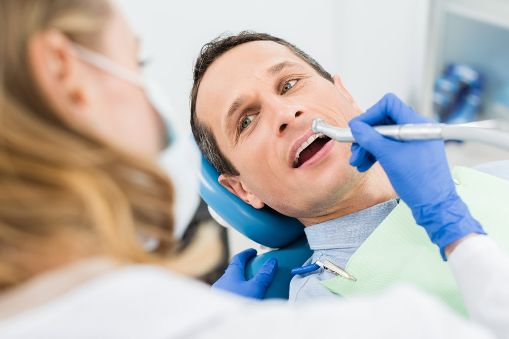Photo of a male patient receiving a dental procedure | Featured image for Relationship between Oral Health and General Health blog from Restore Dental.