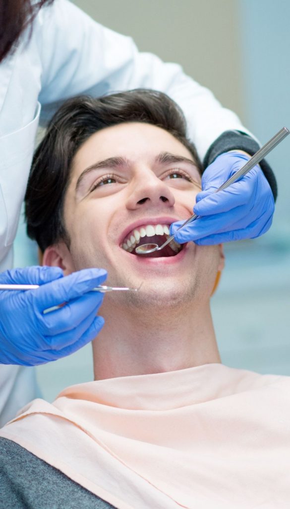 Photo of a smiling patient having their mouth being examined | featured image for Dental Services.