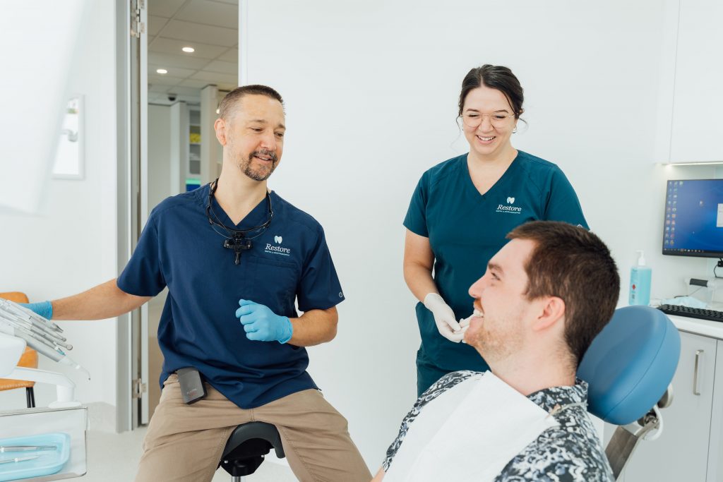 Photo of dentist and assistant chatting with male patient | featured image for General Dentistry Brisbane.