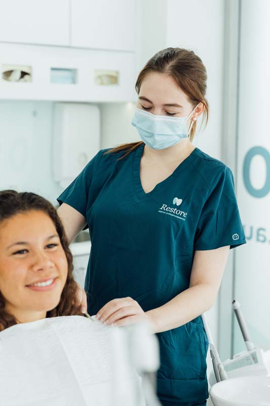 Photo of a Restore Dental assistant helping a client | featured image for Home.
