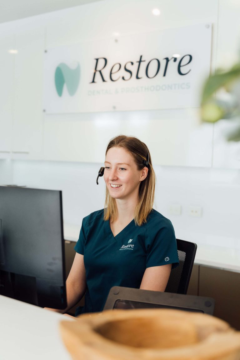 Smiling receptionist at work | Featured image for Dental Fear page by Restore Dental.