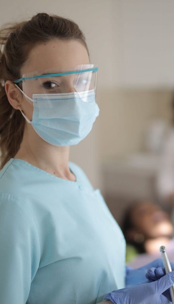 Dentist holding a dental tool while wearing a mask and eye-shield | Featured Image for the Dental Services Page of Restore Dental.