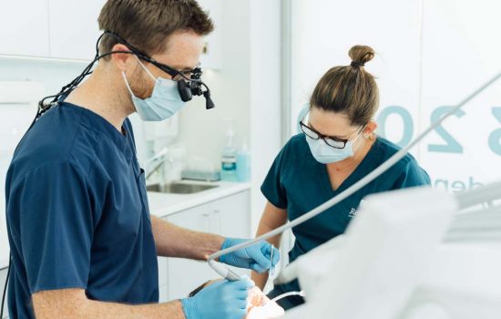 Photo of Restore Dental dentists performing a procedure on a client | featured image for Head and Neck Cancer Rehabilitation.